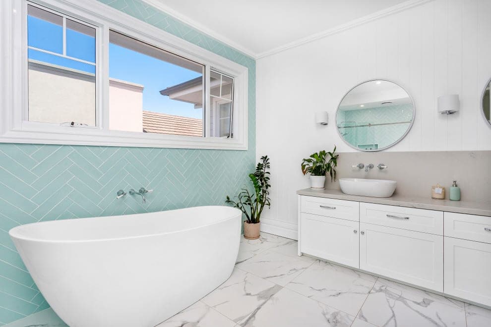Bathroom with freestanding bath, herringbone feature tiles and round mirror