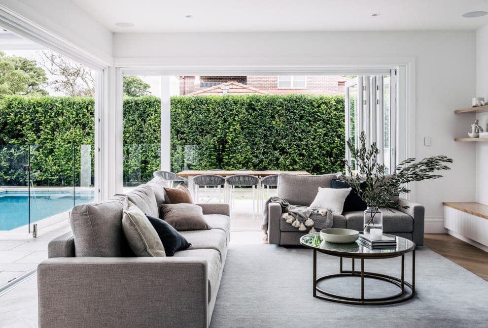 Open-plan living room with grey sofa opening through sliding doors to a covered alfresco