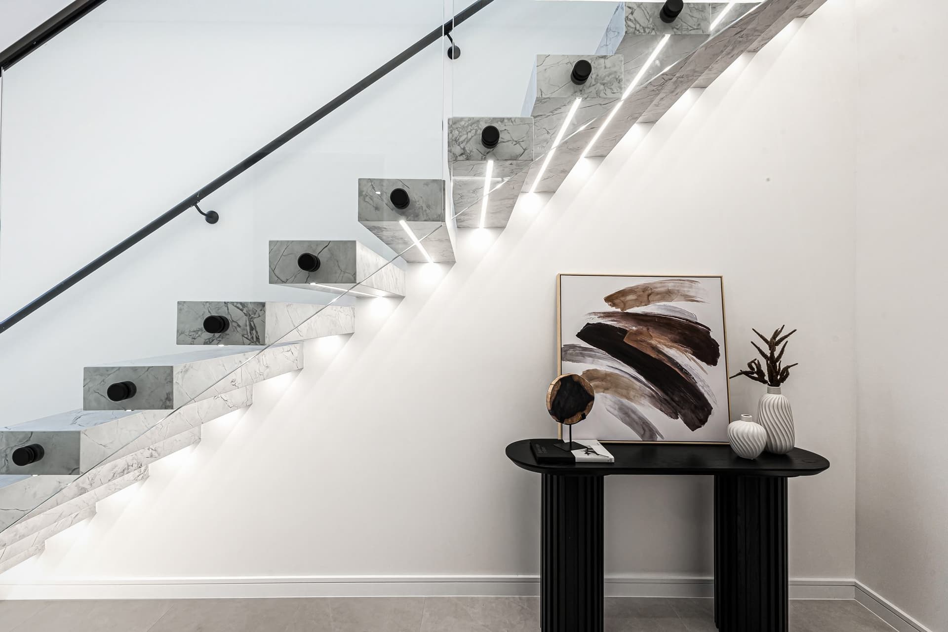 Marble staircase, glass balustrade and warm interior details in a Buildana home