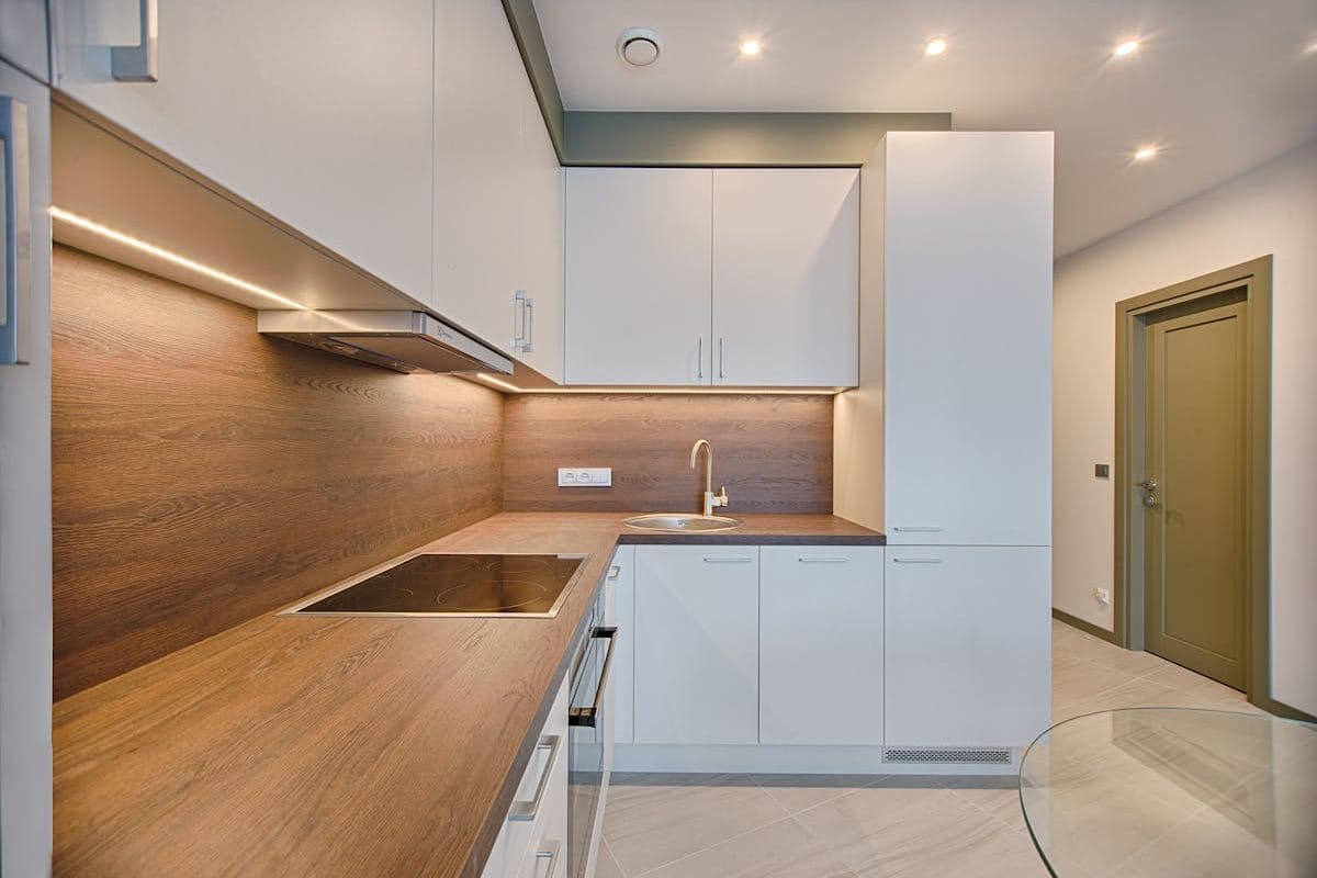 Compact kitchen with white cabinetry and timber finishes