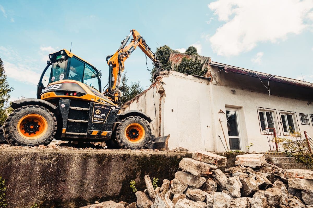 Excavator demolishing an existing house