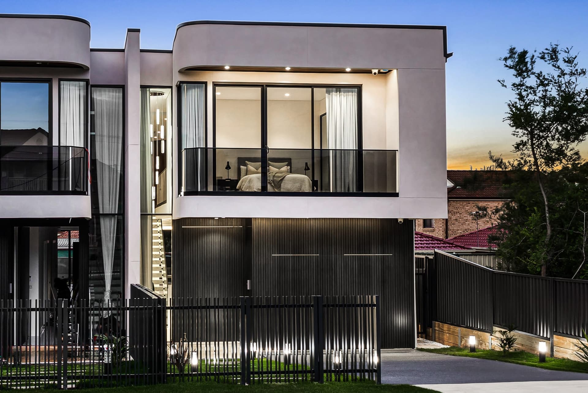 Curved facade and warmly lit interiors of Buildana’s Smart Street home in Fairfield Heights